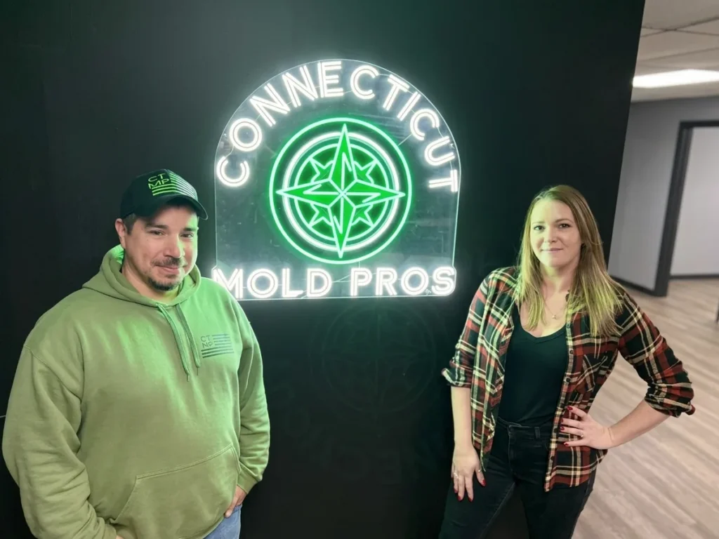 CT Mold Pros owners in front of the Connecticut Mold Pros logo sign